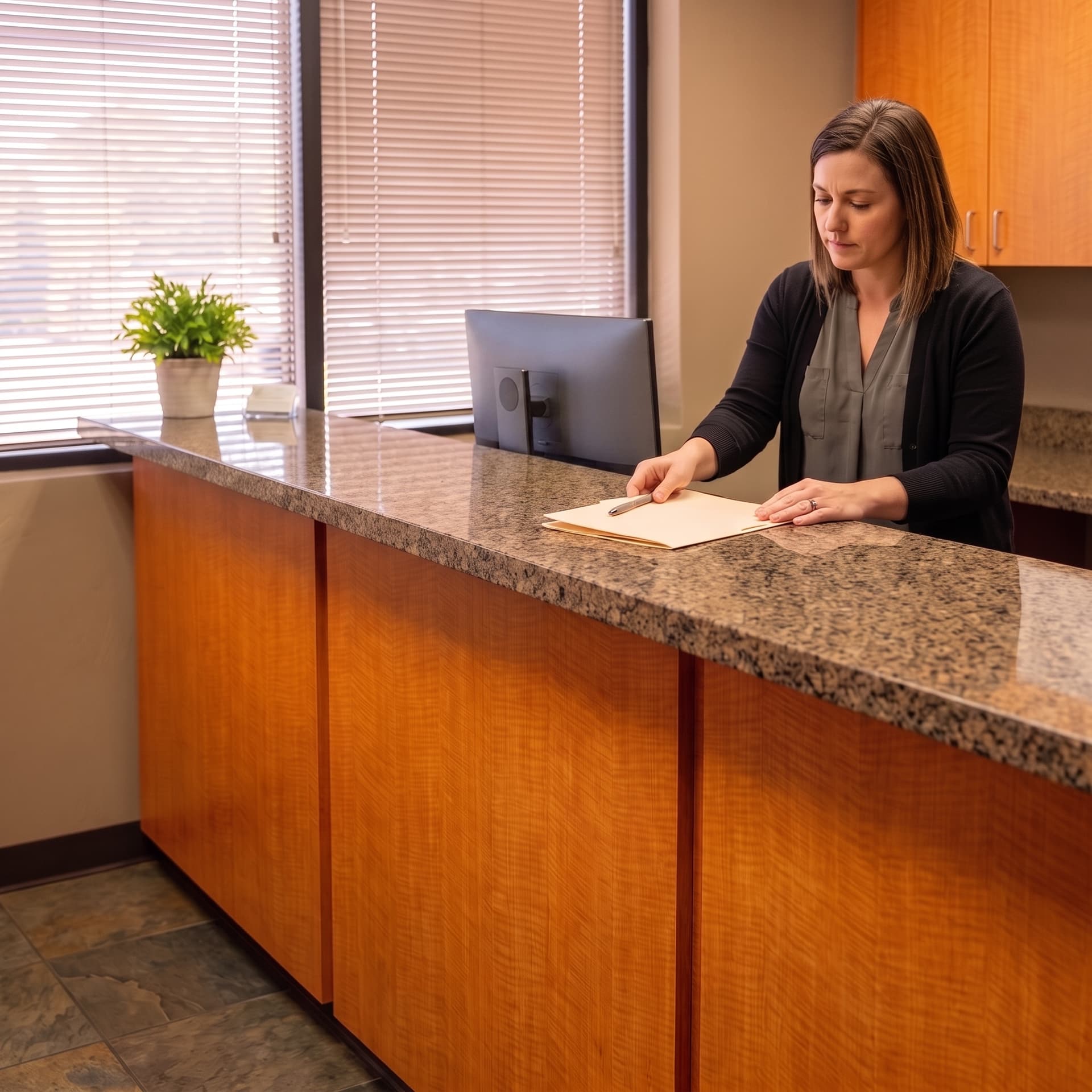A receptionist setting a closed folder and a pen down on the granite front desk