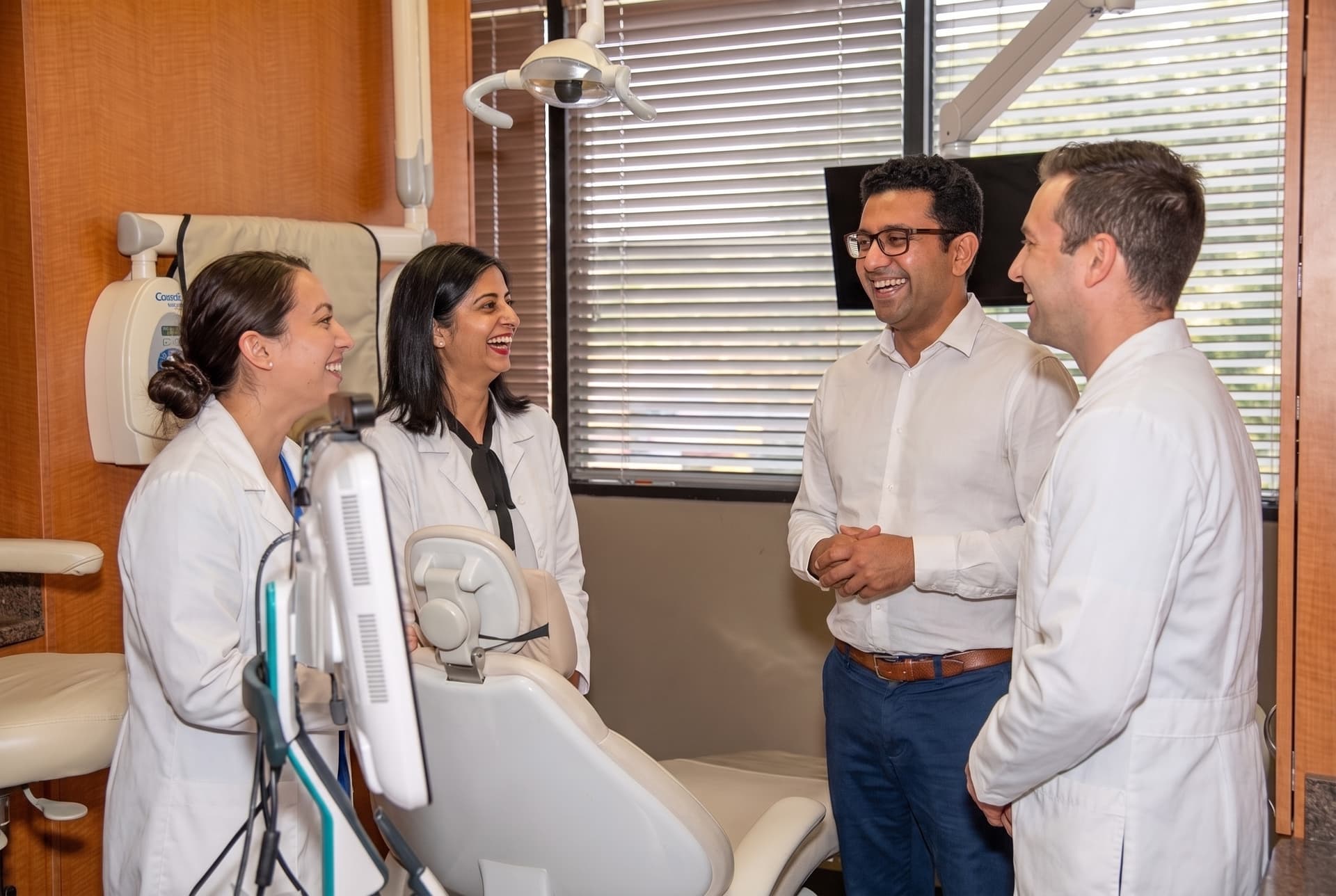 Team members laughing with a patient in the treatment room during a relaxed moment