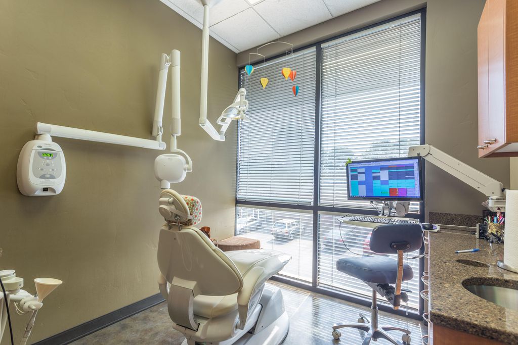A treatment room with the dental chair beside a large window and a chairside monitor